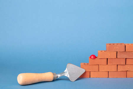 Blocks of red bricks, masonry trowel on a gray-blue background.の写真素材