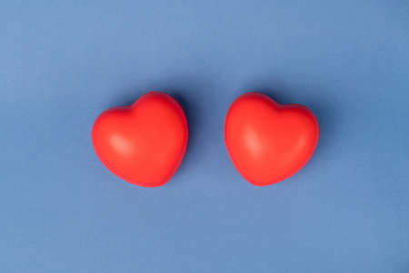 Two rubber red hearts on a blue background with space for text.の写真素材