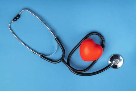 Stethoscope and rubber red heart on a blue background with space for text. Heart health, healthcare concept. Flat layの写真素材