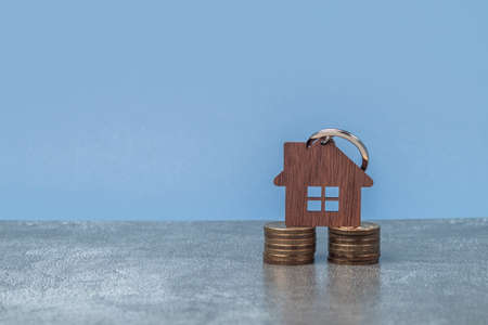 Model of a wooden house on a foundation of coins in piles. The concept of savings and savings to buy a house. Business investmentの写真素材