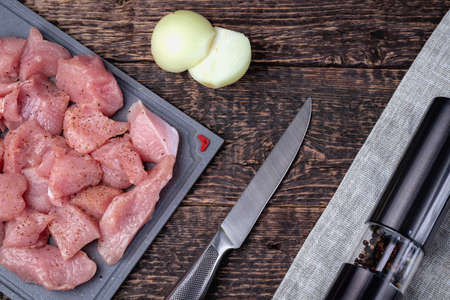 Sliced meat, knife, onion and pepper shaker on an old textured wooden surface. Flat layの写真素材