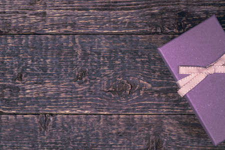 Gift purple box with ribbon on the background of the texture of the old wood.の写真素材