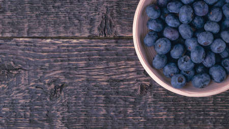 Clay bowl with blueberries on the texture of an old wood.の写真素材