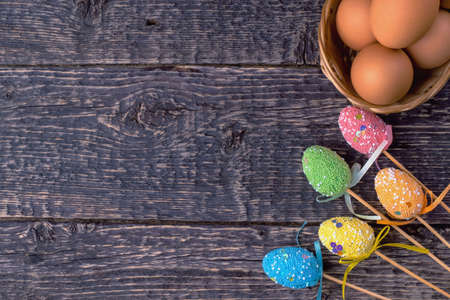 Wicker basket with eggs and decorative bright Easter decorations on the background of the texture of the old wood.の写真素材