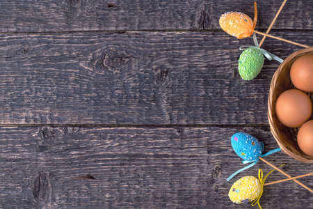 Wicker basket with eggs and decorative bright Easter decorations on the background of the texture of the old wood.の写真素材