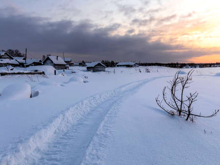 Winter landscape with a trail winding along the outskirts of the village in the snow.の写真素材