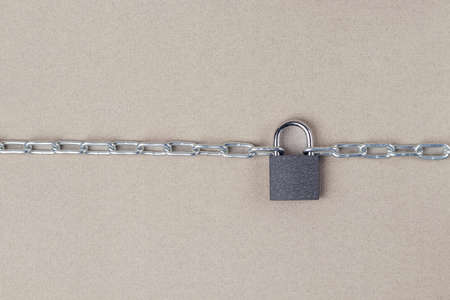 The links of a metal chain are fastened with a padlock on a gray background. security conceptの写真素材