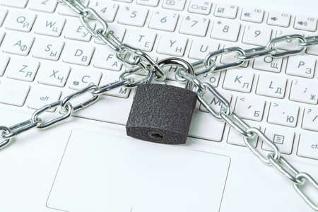 Metal chain and padlock close-up on the background of a white laptop keyboard. security conceptの写真素材