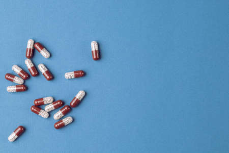 Colored capsules with medical drugs on a blue background.の写真素材