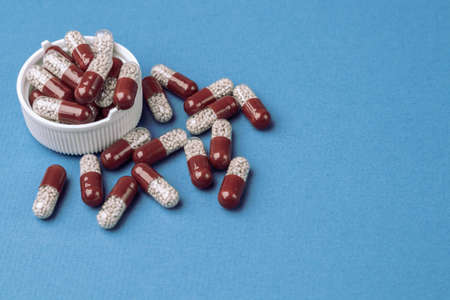 Colored capsules with medical drugs on a blue background.