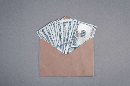 Dollar bills in a paper envelope on a gray background. Bonus, reward, benefits conceptの写真素材