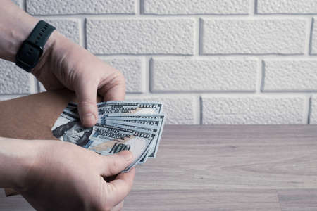 Male hands count dollar bills in a paper envelope. Bonus, reward, benefits conceptの写真素材
