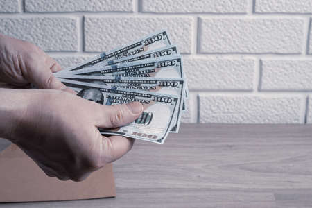 Male hands count dollar bills in a paper envelope. Bonus, reward, benefits conceptの写真素材