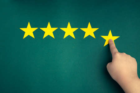 The customer's hand gives a five-star rating on a green background. The concept of service quality assessment.の写真素材