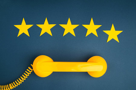 Five star rating and yellow retro phone on a blue background. customer service quality control.の写真素材