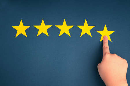 The customer's hand gives a five-star rating on a blue background. The concept of service quality assessment.の写真素材