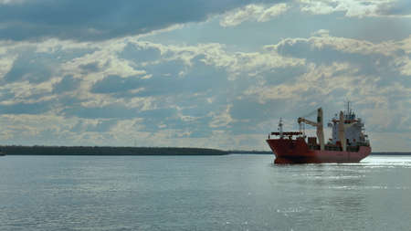 A cargo ship is in the roadstead on a large river. backlight from the sunの写真素材