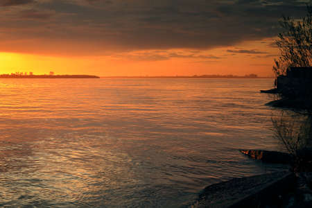 Beautiful diffused sunset light over the river. Stones on the shoreの写真素材