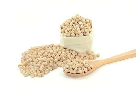 Dry Raw Chick Peas Seeds (very rich of proteins) spilled on pile, in wooden cooking spoon and in white fabric bag over white background. の写真素材