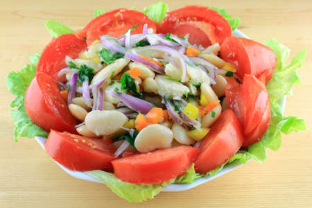 Salad from Boiled Huge Lima Beans mixed with Seasonings and dressed with Olive Oil, Balsamic Vinegar, Key Lime Juice, served in Porcelain Bowl over Lettuce Leaves and decorated with chopped Tomatoes     の写真素材