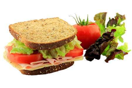 Sandwich from Whole Grains Bread, Ham and Cheese garnished with organic fresh Sliced Tomatoes and Leaves Lettuce in front of  blurred  whole tomato and leaf of Lettuce isolated on white background  の写真素材