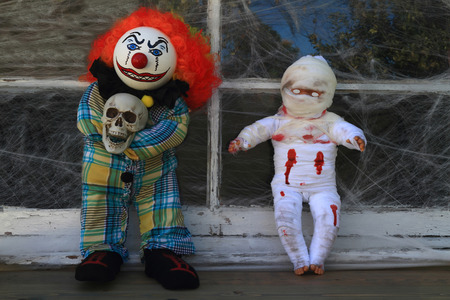 Typical Halloween Decoration from Scary Characters dolls (Clown Killer and Mummy)   in front of old window cover by spider web.