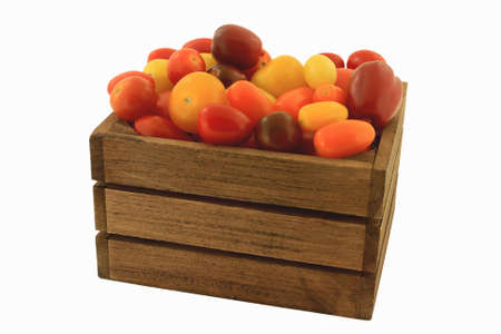 Different colors (red, yellow, orange, brown, Colorful) and shapes Organic mini tomatoes in wooden crate over white backgroundの写真素材