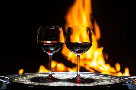 two glasses of wine on the background of fireの写真素材