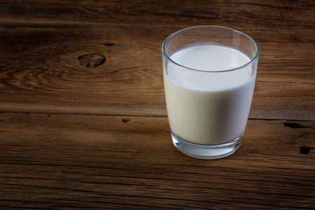 glass of milk on wooden backgroundの写真素材