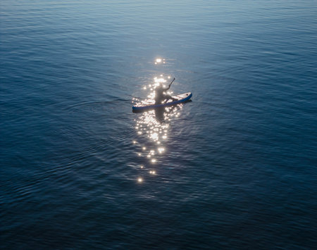 Aerial view of a person on a paddleboard on the sea with sun reflection in waterの写真素材