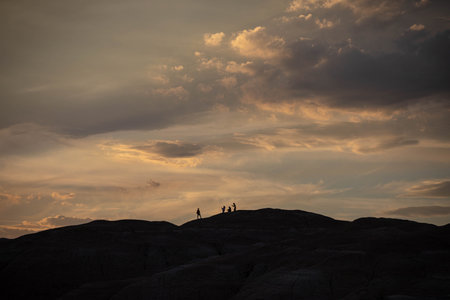 Silhouette of a group of people walking on the rocks at sunsetの写真素材