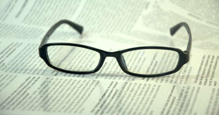 Black-framed glasses lie on the page of the magazine.