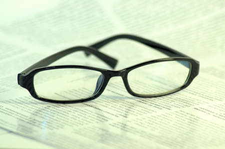 Black-framed glasses lie on the page of the magazine. Close up.の写真素材