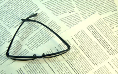 Black-framed glasses lie on the page of the magazine. Close up.の写真素材