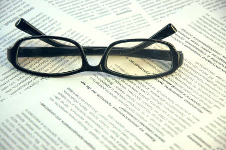 Black-framed glasses lie on the page of the magazine. Close up.の写真素材