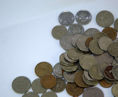 Coins laid out in a chaotic manner on a white background. Close up.の写真素材