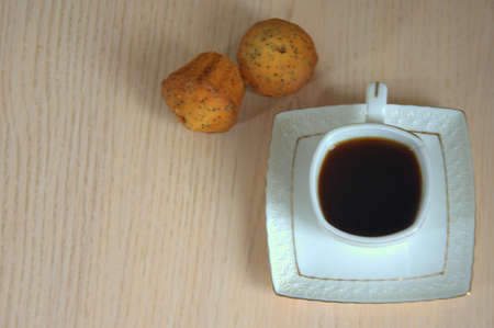 A cup of black coffee and two cupcakes. Close-up shot.
