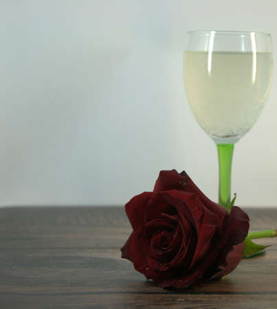 Two glasses of champagne and a red rose on a wooden table. Close-up.の写真素材