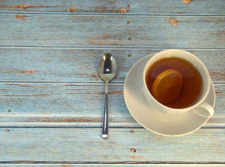 A cup of tea with a slice of lison and a spoon lie on a wooden table. Close-up.の写真素材