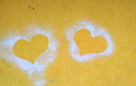 Silhouettes of two hearts on a yellow concrete wall. Close-up.の写真素材