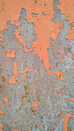 Metal surface with peeling orange paint closeup shot.