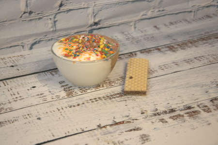 Chocolate and vanilla ice cream with decor and waffle lie on a wooden table.