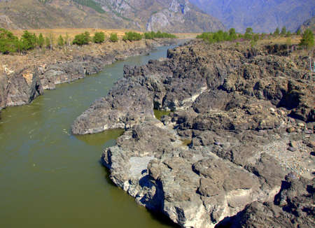 The mountain river Katun carries its turquoise waters through the rocky shores and steep cliffs of...