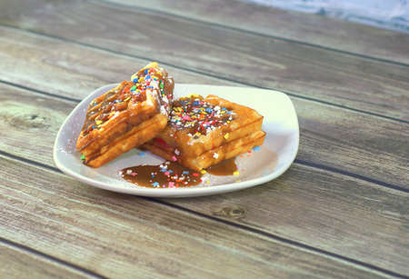 Two Viennese waffles in chocolate glaze with a sprinkle on a ceramic plate.の写真素材