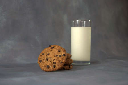 Glass cup with milk and several oatmeal cookies on a gray abstract background.の写真素材