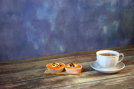 Two delicious fresh cupcakes on a textile napkin and a cup of tea on the table. Close-up.