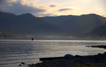 Late evening on the lake surrounded by mountain peaks. Teletskoye Lake, Altai, Russia.