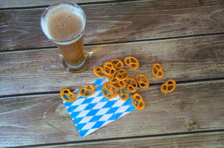 A tall glass of light beer on a traditional napkin and a group of salty pretzels. Close-up.の写真素材