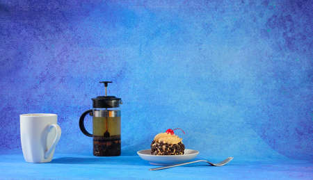 Sweet breakfast, sponge cake with chocolate and cherry, tea pot with white ceramic mug. Close-up.の写真素材