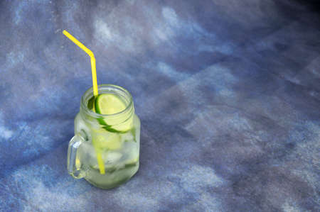 Glass mug of refreshing mojito with ice and a slice of lime on a gray background. Close-up.の写真素材